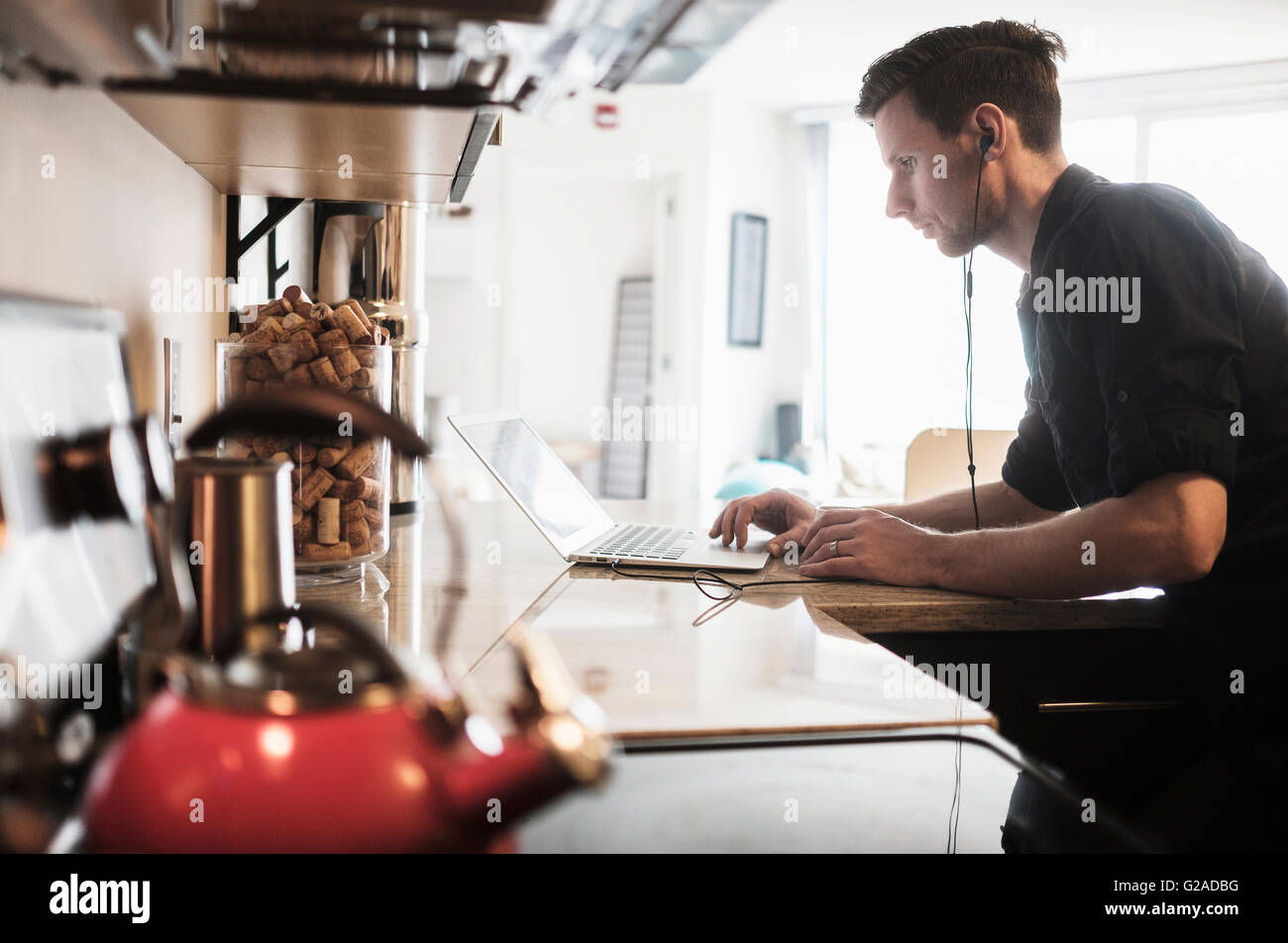 Man working on laptop computer in kitchen Banque D'Images