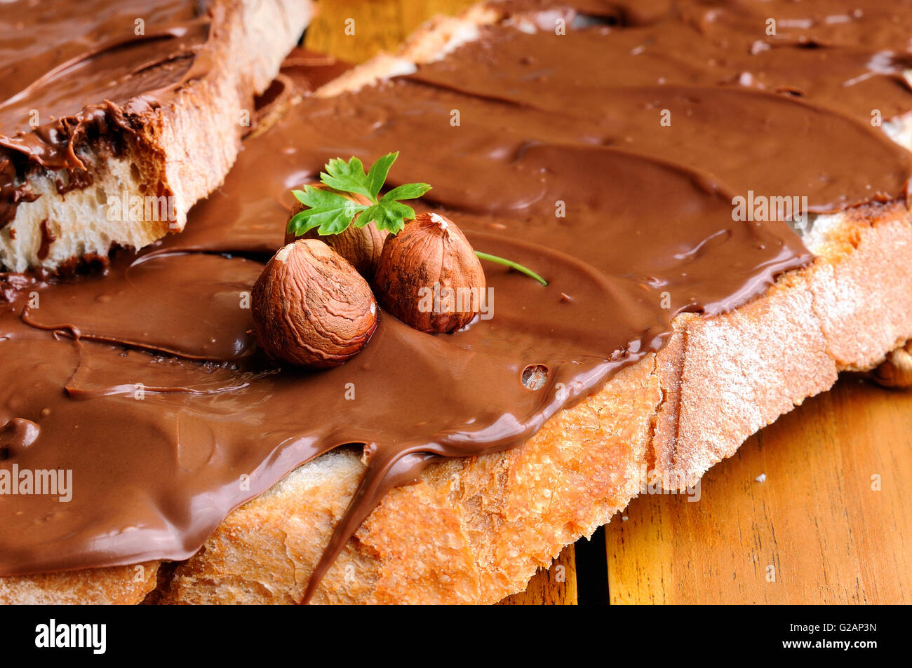 Deux tranches de pain avec la crème au chocolat et noisettes sur une table en bois close up. Banque D'Images