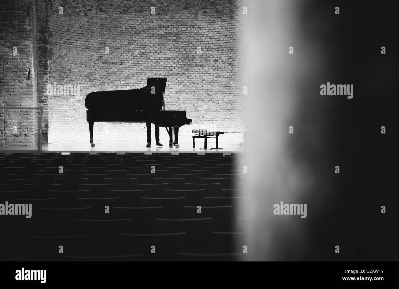 Piano à queue de concert en salle de concert avec murs de briques noir et blanc Banque D'Images