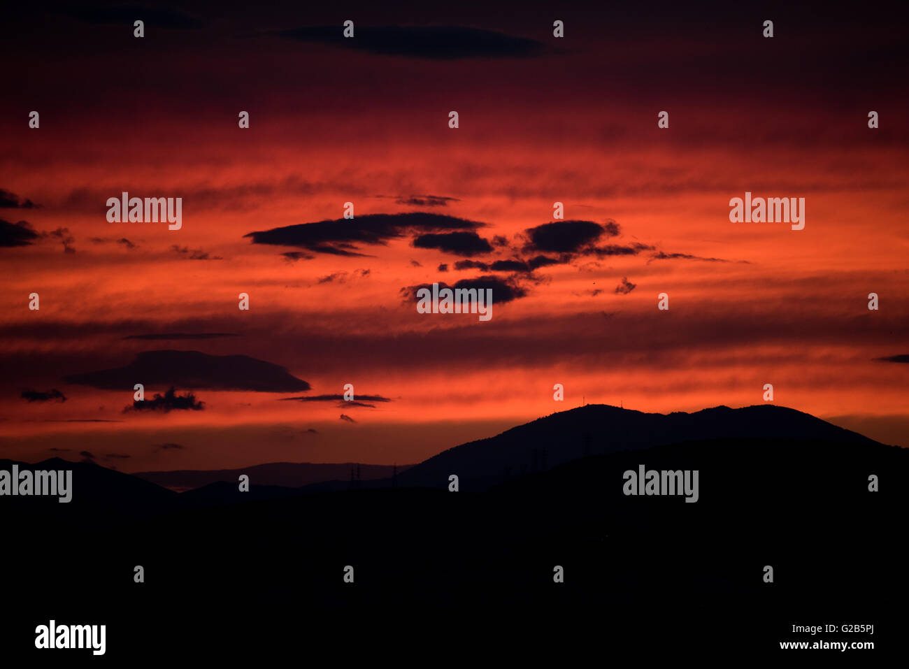 Coucher de soleil rouge sur la montagne Egaleo Athènes Grèce // ATHÈNES, Grèce — Un coucher de soleil rouge spectaculaire illumine la ligne d'horizon ouest d'Athènes. Le soleil se couche derrière la chaîne de montagnes Egaleo, qui forme la frontière ouest de la ville, atteignant une altitude de 468 mètres (1 535 pieds). Les silhouettes des bâtiments dans l'ouest d'Athènes et peut-être des parties du Pirée, situées à environ 12 km (7,5 miles) au sud-ouest du centre d'Athènes, sont visibles contre le ciel éclatant. Cette scène, commune à Athènes en raison de son climat méditerranéen, est intensifiée par les conditions atmosphériques et l'altitude de la ville de 70-300 mètres (230-984 pieds Banque D'Images