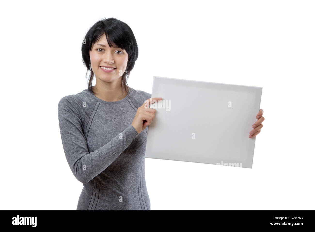 Haut du corps tourné d'une jeune femme slim modèle de remise en forme, vêtu d'un long sleeved top gris, holding a blank white board. Banque D'Images