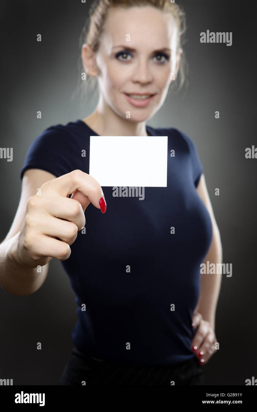 Business model holding a small business card en face d'elle. carte d'affaires est au point et le modèle est floue. Tourné sur un fond gris Banque D'Images