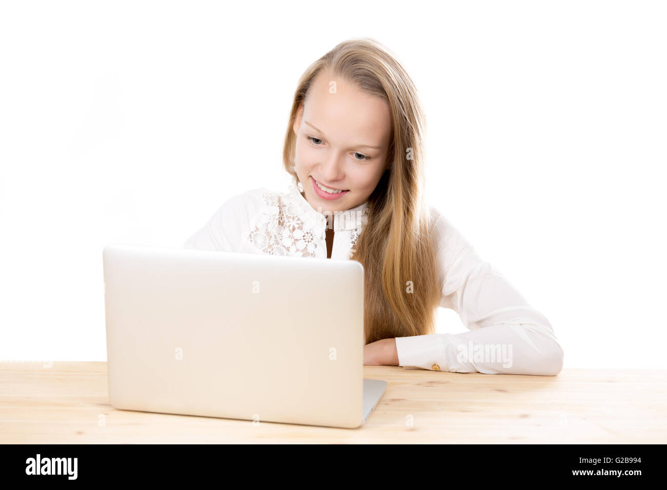 Portrait of smiling casual caucasian belle jeune femme portant uniforme blanc chemise, assis au bureau, using laptop Banque D'Images