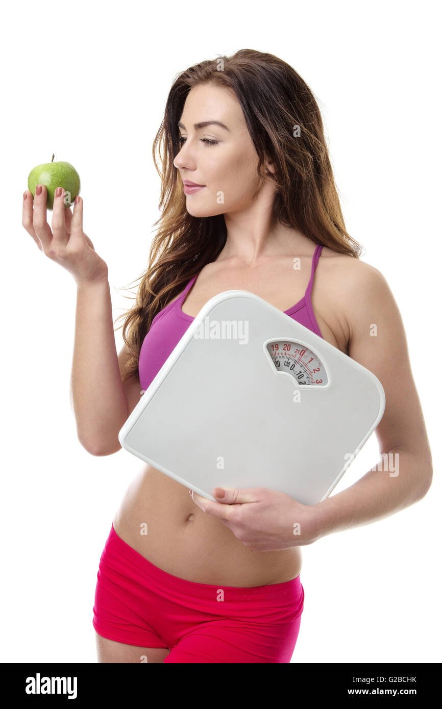 Jeune Modèle de remise en forme tenant une pomme verte et certaines échelles de poids isolated over white background Banque D'Images