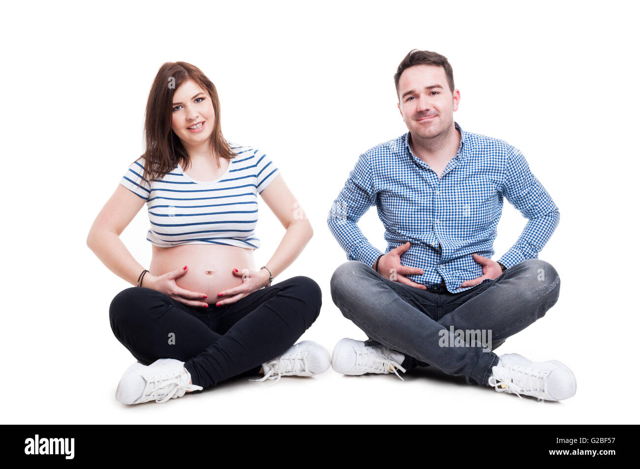 Couple heureux d'une joyeuse mari debout et tenant les mains sur son ventre comme femme enceinte isolated on white Banque D'Images