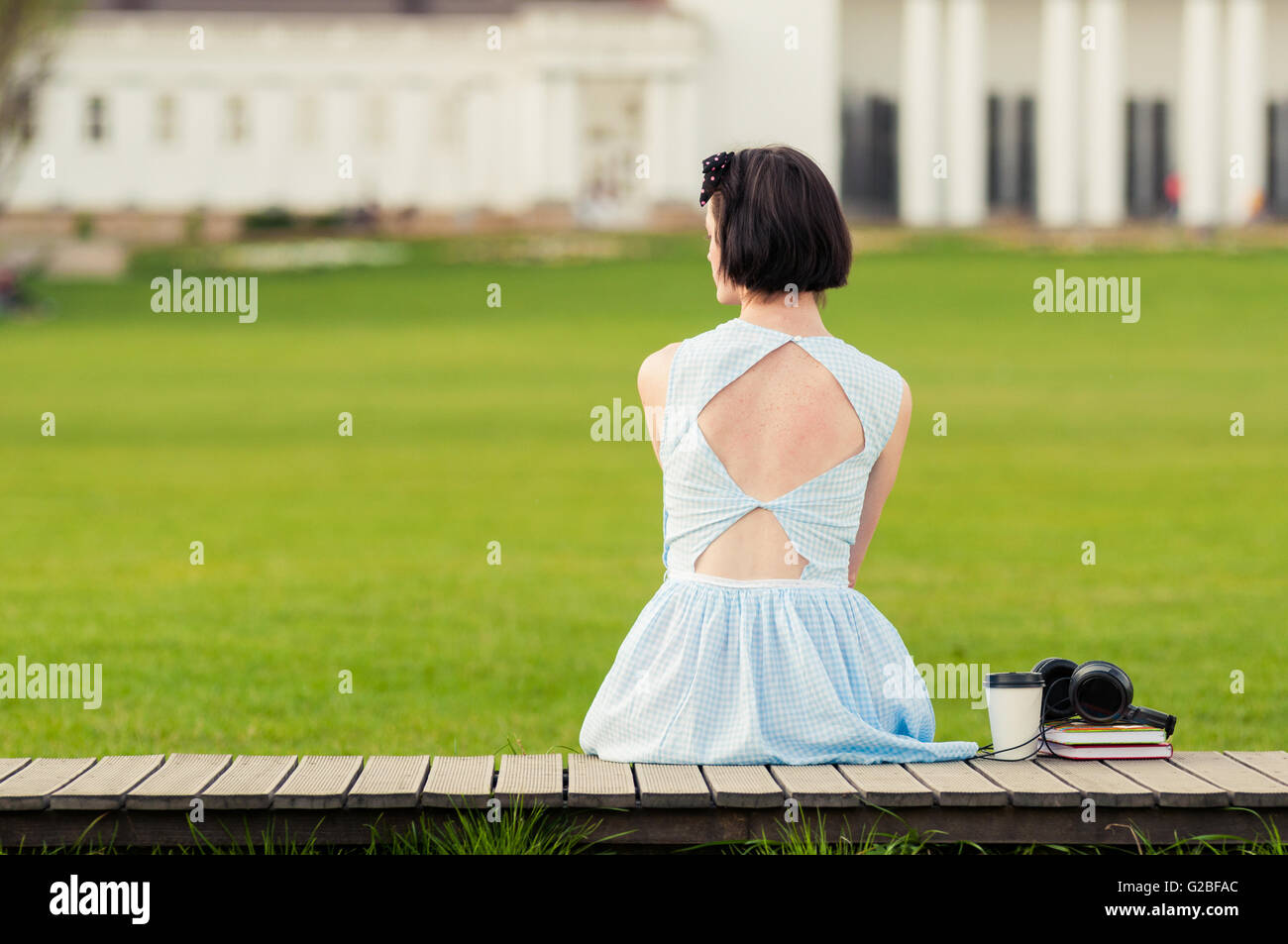 Jeune femme avec robe vintage avec commandes de retour à l'appareil photo dans le parc et vous détendre dans une journée ensoleillée Banque D'Images