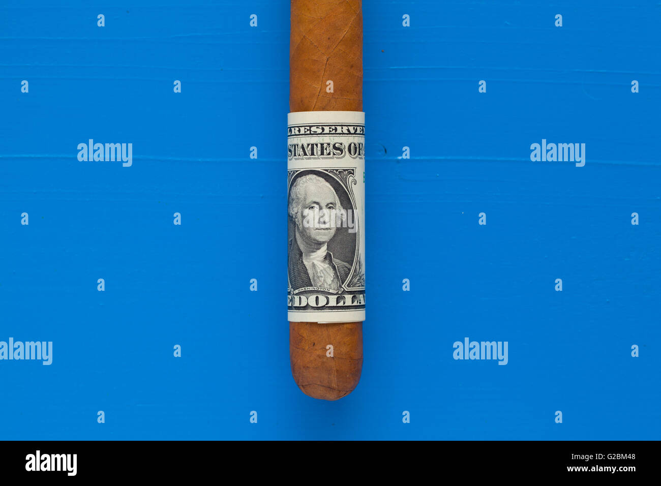 Détail de luxe cigare cubain avec du dollar américain sur le bureau bleu Banque D'Images