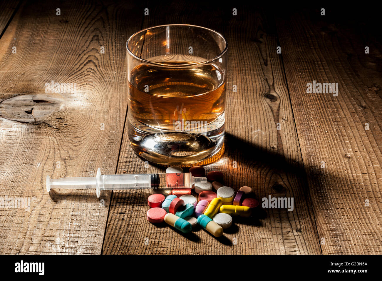 L'alcool, comprimés et la seringue sur la table avec ombre Banque D'Images