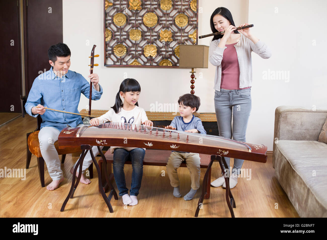 Jeune famille jouant des instruments de musique traditionnels à la maison Banque D'Images