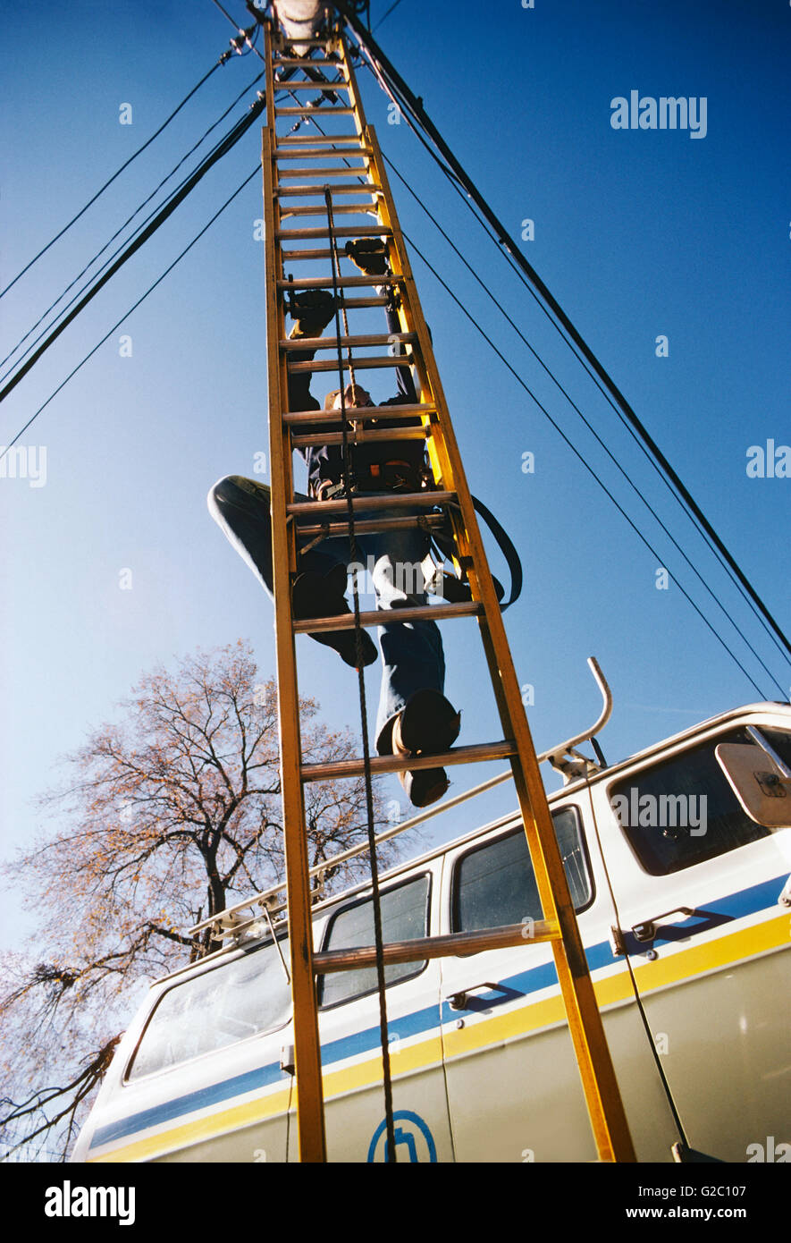 L'utilitaire mâle worker climbing ladder pour accéder aux fils électriques aériens & communication Banque D'Images