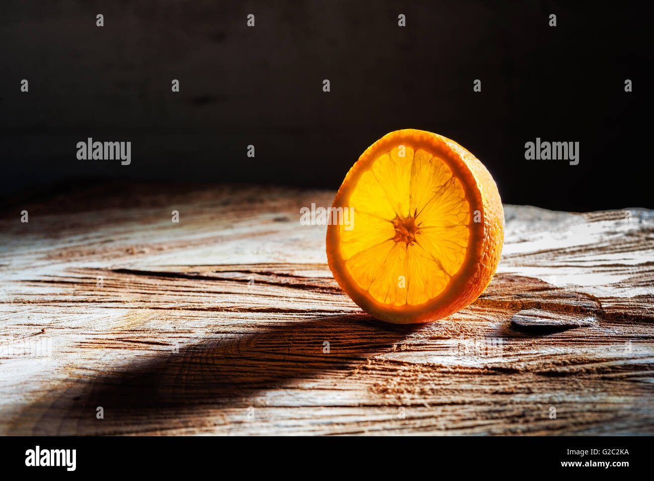 Tranche d'orange rayonnant de lumière arrière et grande ombre sur table en bois avec copie espace Banque D'Images