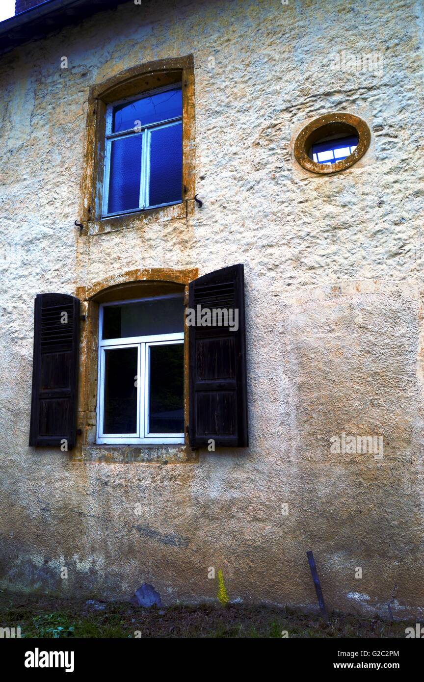Ancienne façade avec un oeil de boeuf et une fenêtre avec des volets en bois. Banque D'Images