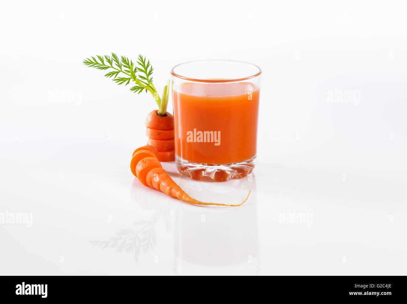 Le jus de carotte frais en verre sur fond blanc Banque D'Images