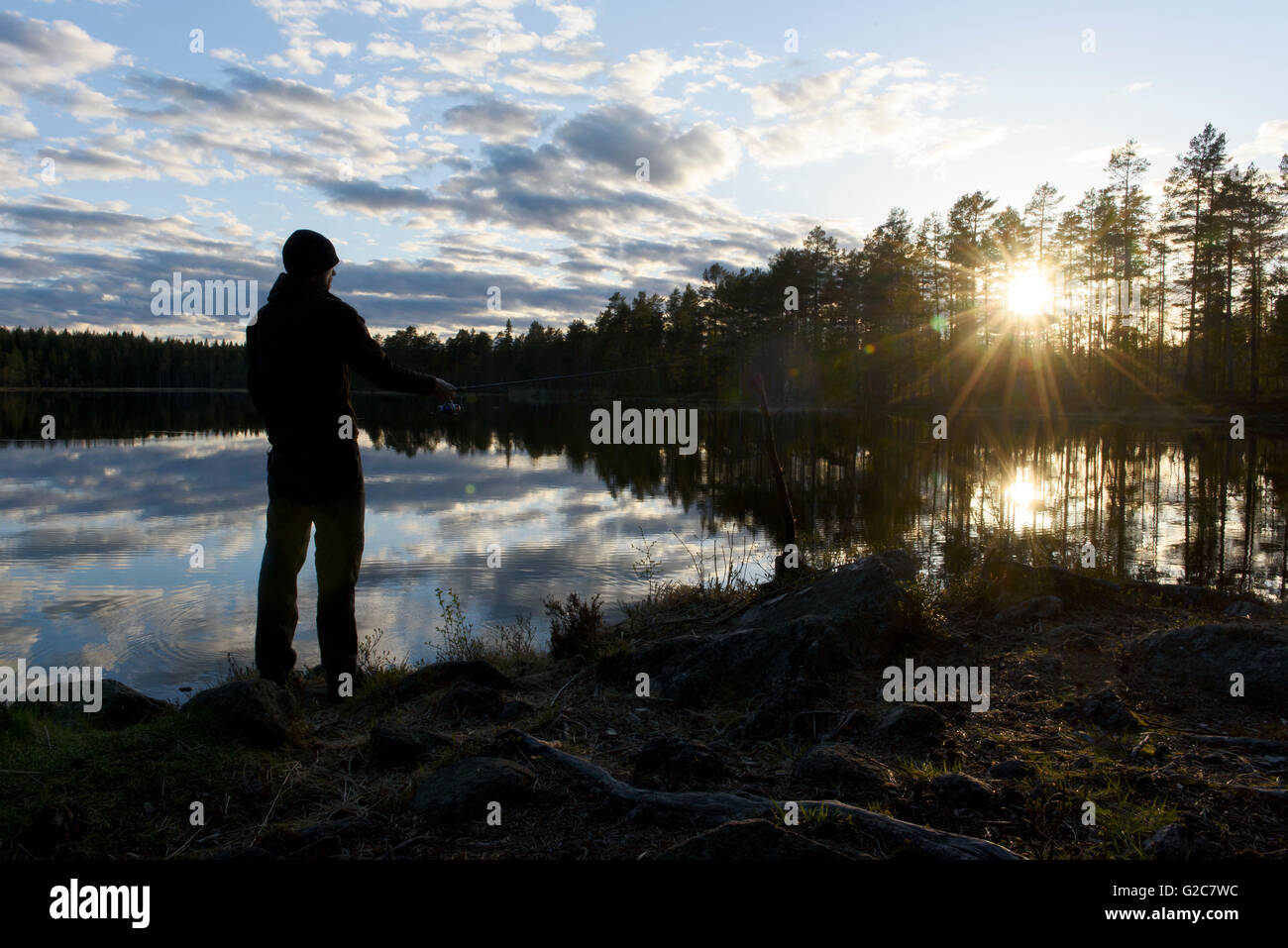 La pêche dans un lac au coucher du soleil, Bergslagen, Suède Banque D'Images