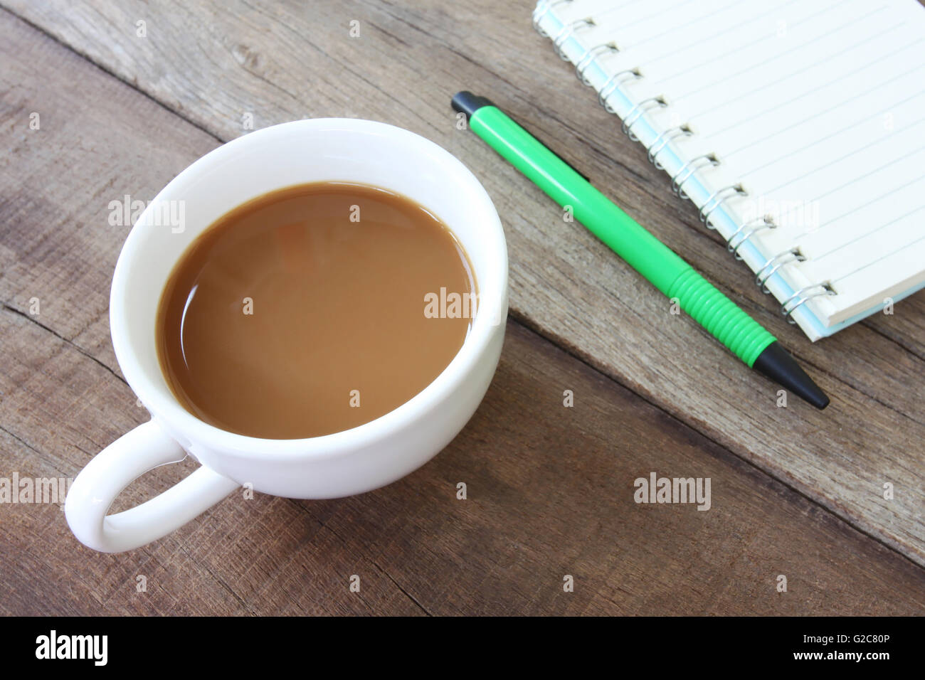 Tasse à café et blanc ont vide,livre stylo vert sur un sol en bois et le concept de boisson. Banque D'Images