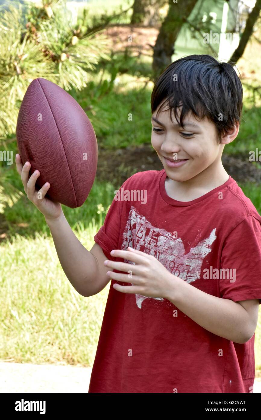 Un jeune garçon jouant au football dans un champ Banque D'Images