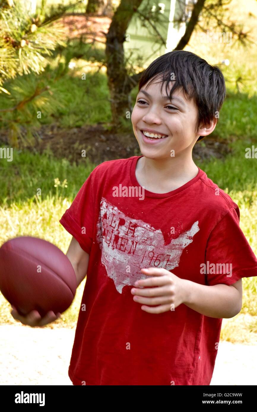 Un jeune garçon jouant au football dans un champ Banque D'Images