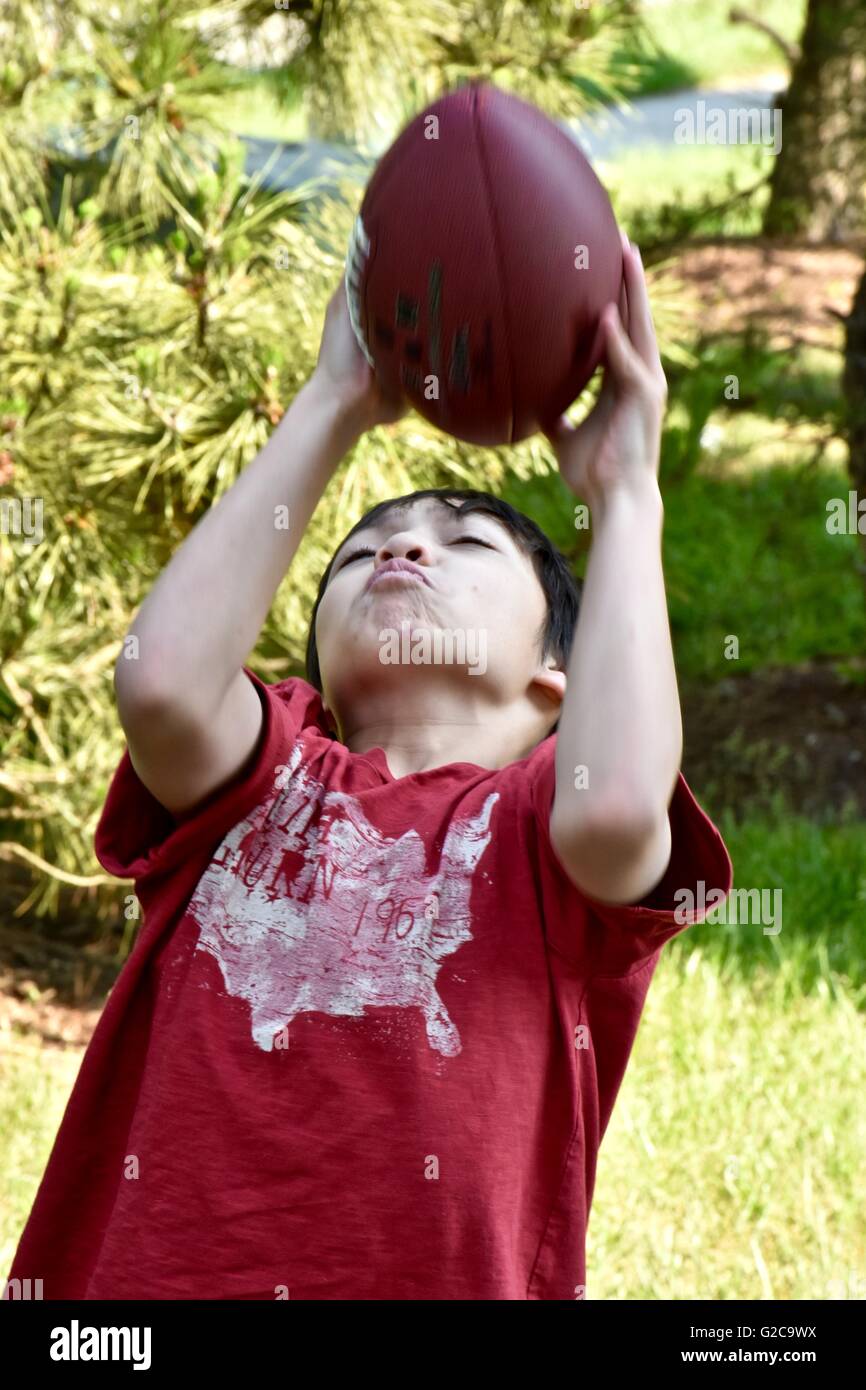 Un jeune garçon jouant au football dans un champ Banque D'Images