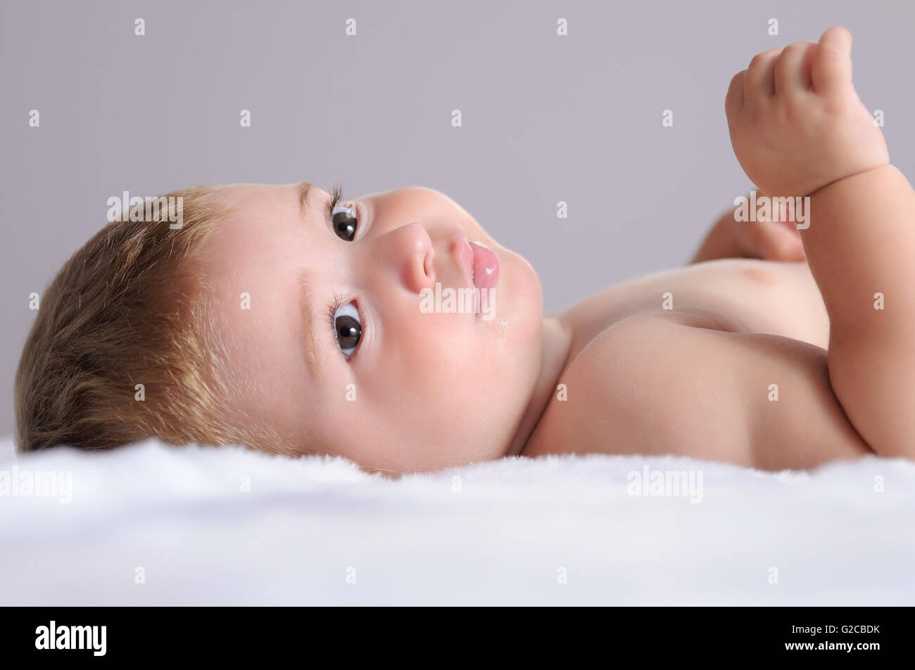 Bébé couché sur une couverture des cheveux blancs et isolé sur fond gris Banque D'Images