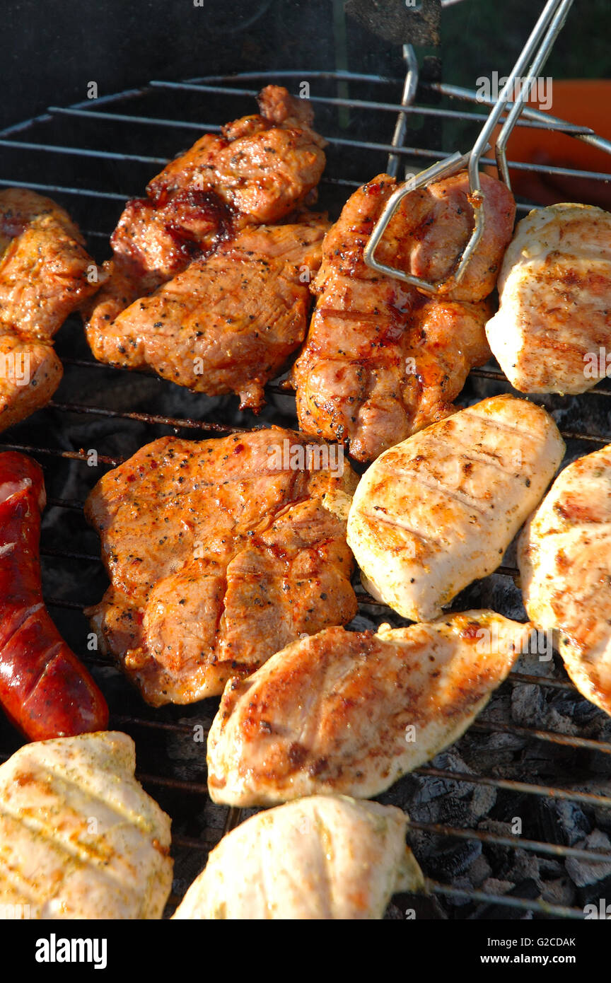 La viande de poulet, de viande de porc et saucisses cuisson sur un barbecue. Banque D'Images