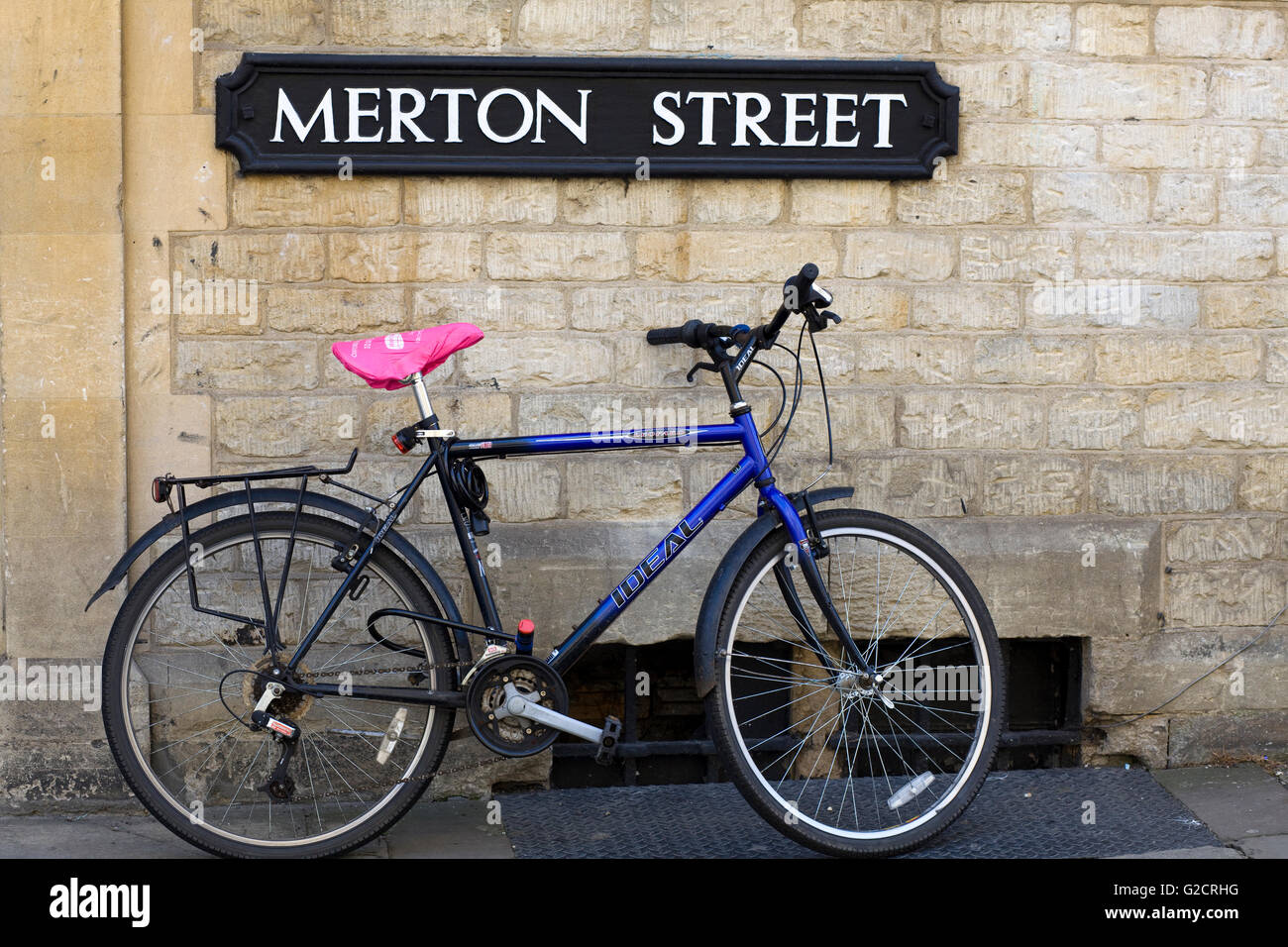 Location appuyé contre un mur de pierre à côté du signe de la rue Merton Oxford Angleterre Banque D'Images Location appuyé contre un mur de pierre à côté du signe de la rue Merton Oxford Angleterre Banque D'Images