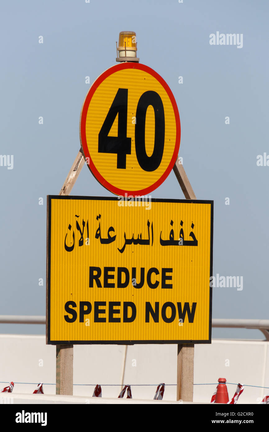 Panneau routier Réduire la vitesse maintenant en anglais et arabe Banque D'Images