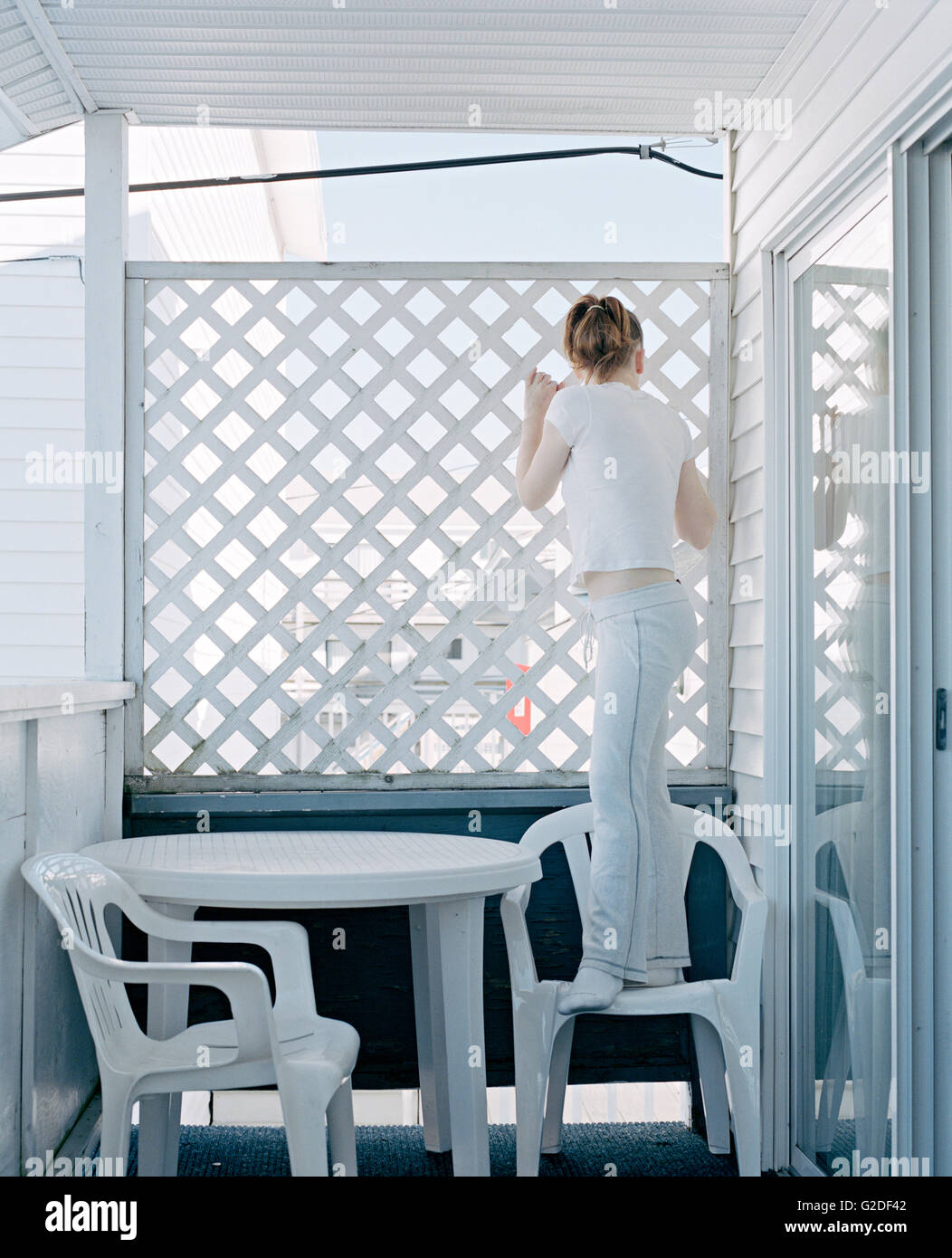 Femme Debout sur le porche en plastique Président Peeking Through clôture en treillis Banque D'Images