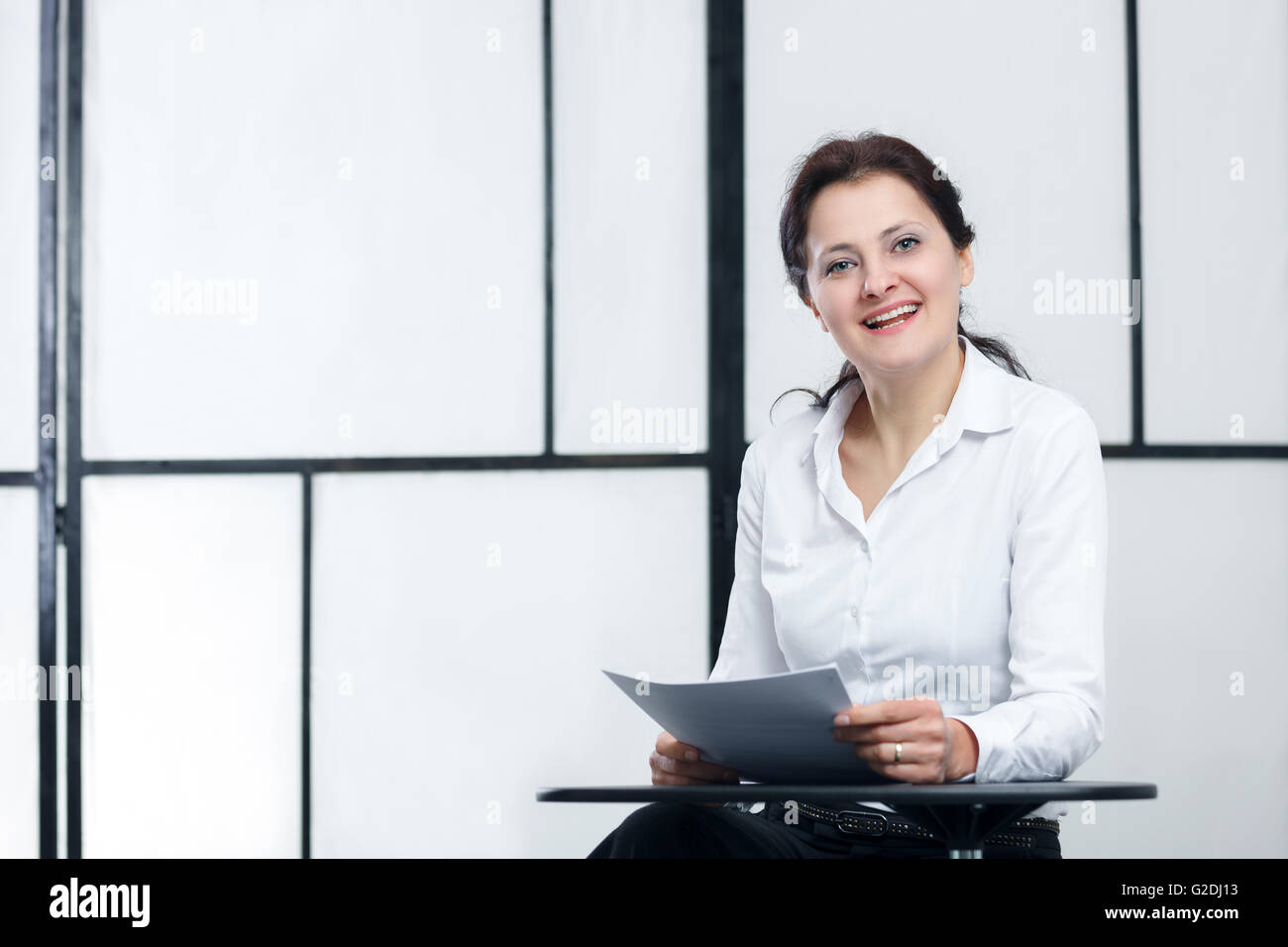 Business Woman sitting on table avec des papiers dans les mains reprendre Banque D'Images