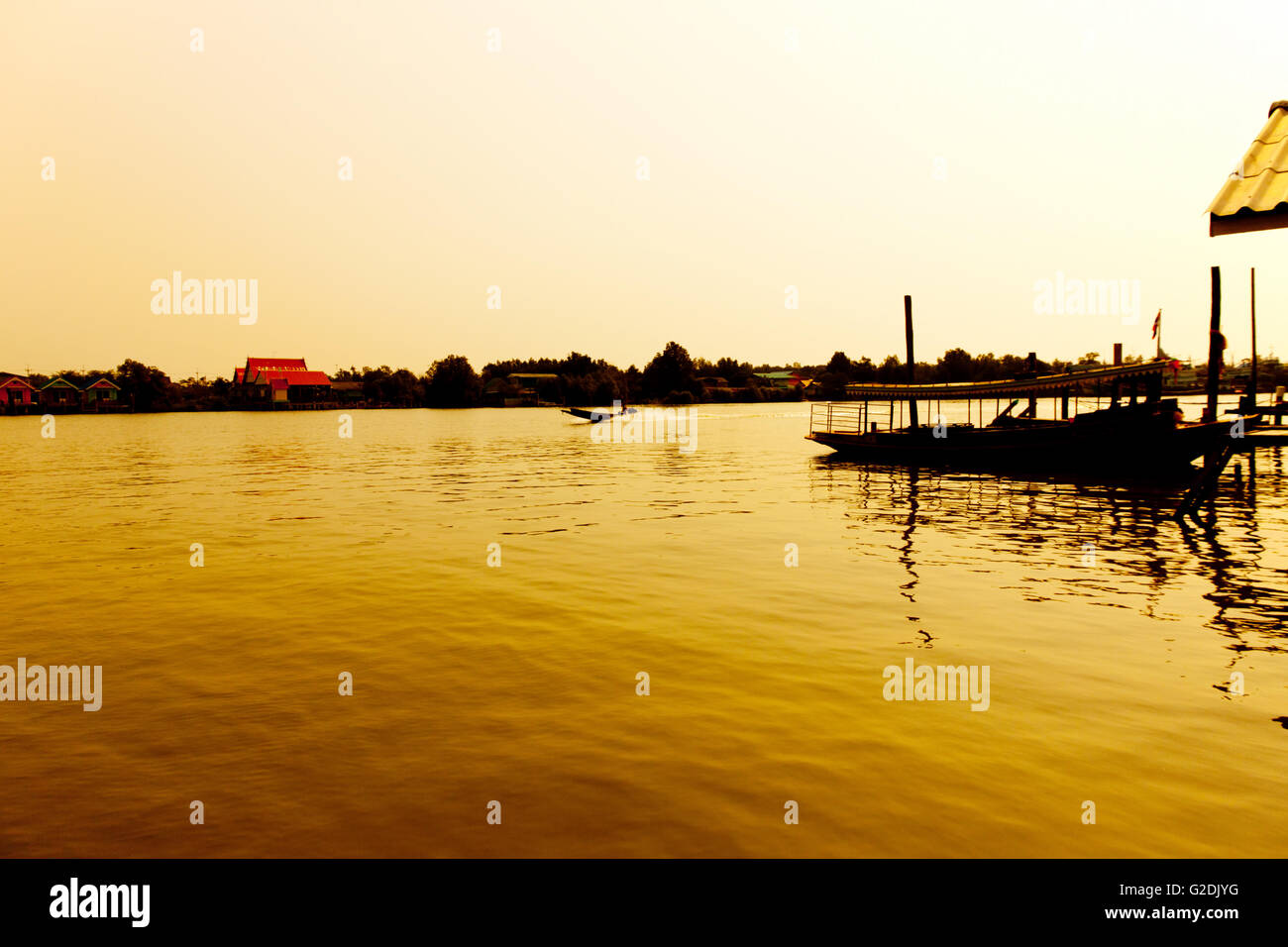 Bois de la longue queue bateau de moteur à la rivière à l'aube d'une lumière dorée. Lever du soleil grâce à silhouette Banque D'Images
