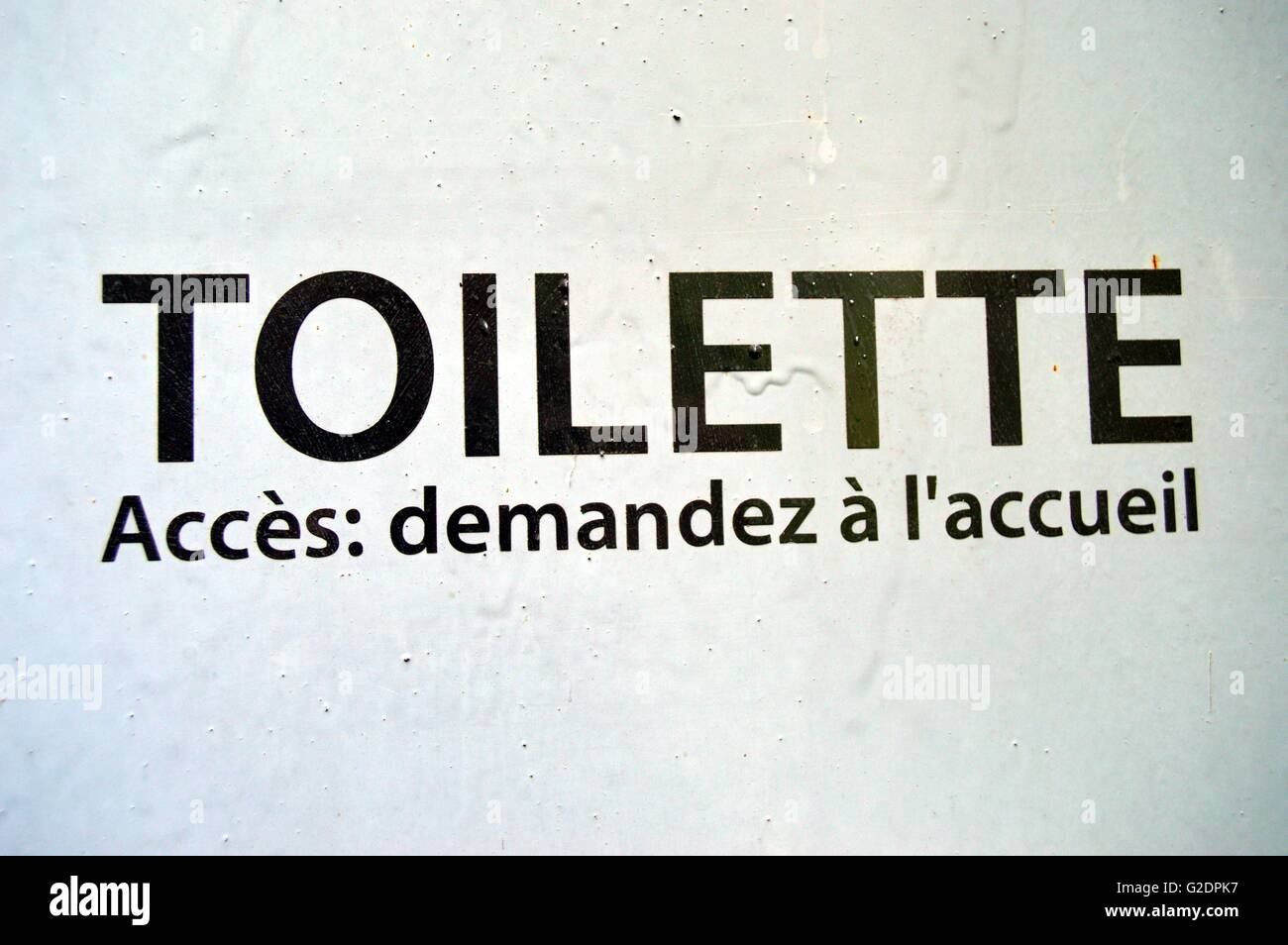 Poster toilettes peint sur une porte de couleur gris avec des sentiers de peinture Banque D'Images