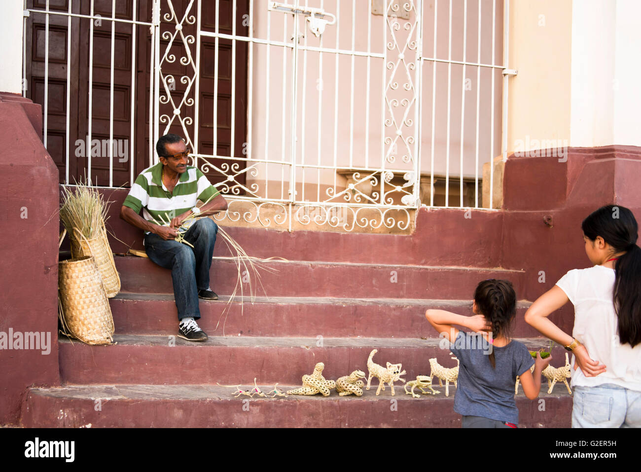 Portrait d'un homme horizontale des bandes de nouage de la canne à sucre feuille dans les ornements des animaux à vendre dans une rue de Trinidad, Cuba. Banque D'Images