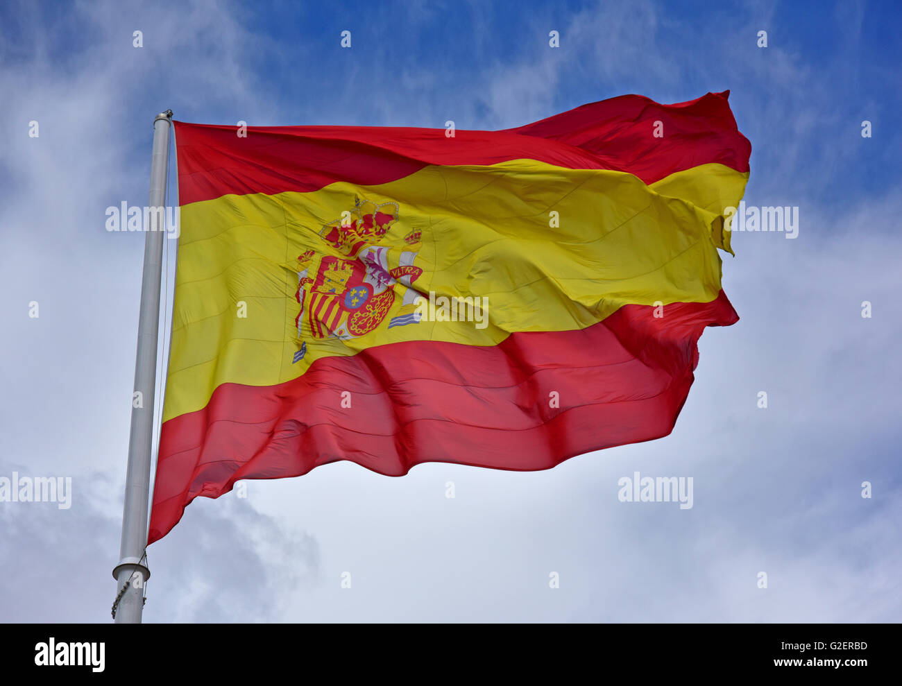 Pavillon de l'Espagne en battant une marche rapide contre une brise de ciel bleu avec des nuages. Banque D'Images Pavillon de l'Espagne en battant une marche rapide contre une brise de ciel bleu avec des nuages. Banque D'Images