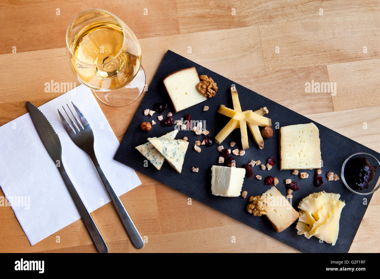 Divers fromages sur une plaque en ardoise et verre de vin blanc dans un bistro français Banque D'Images