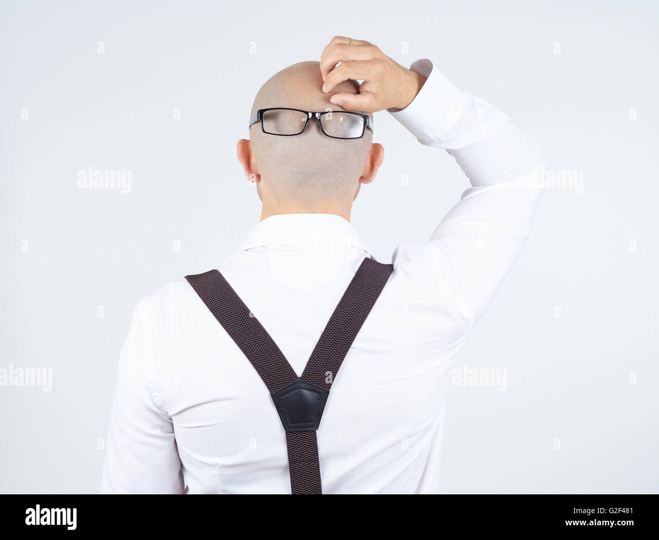 Retour d'un homme à tête d'une chemise blanche avec des lunettes à la nuque gratte la tête. Banque D'Images