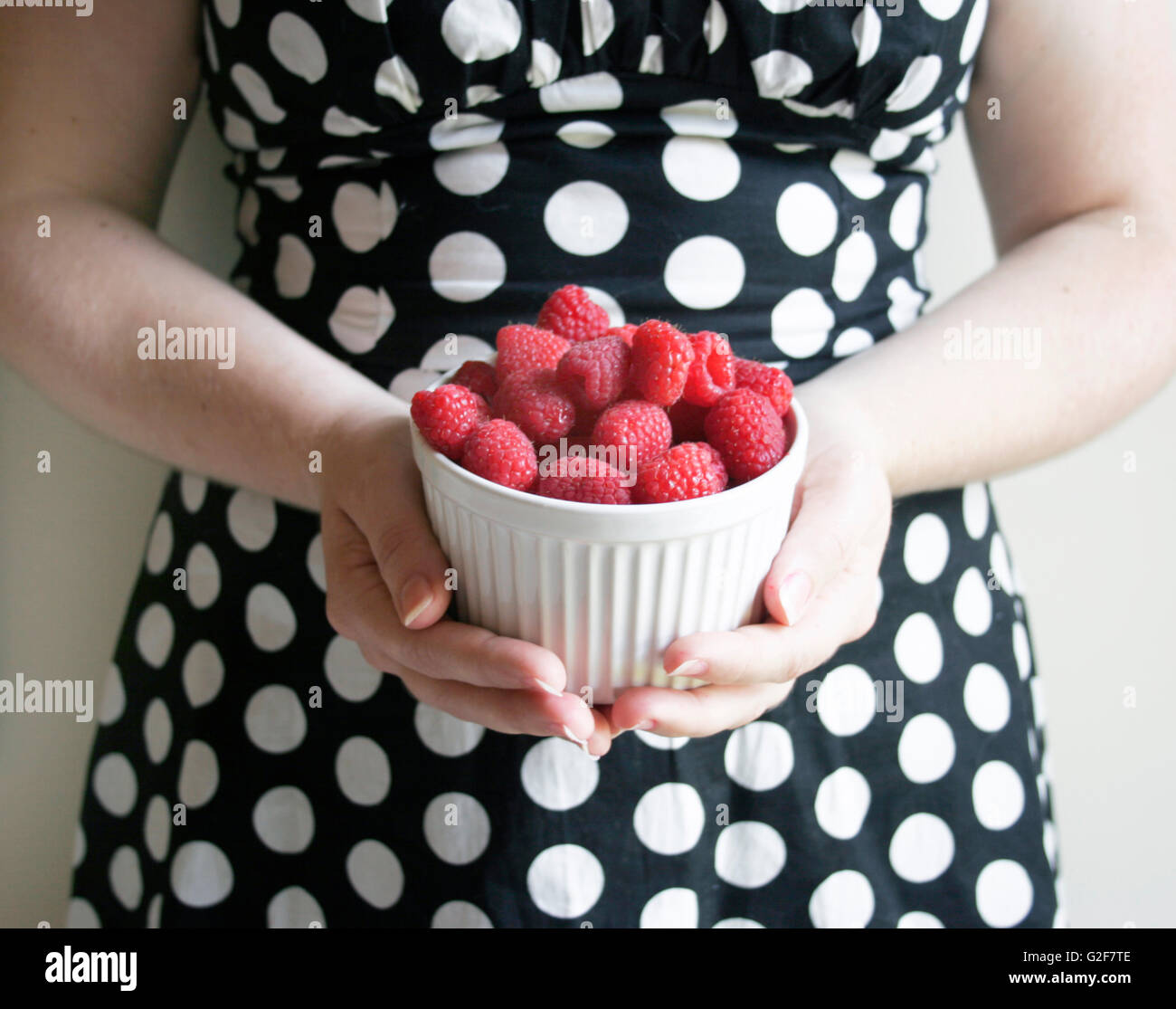 Femme en tenue à pois bol de framboises Banque D'Images