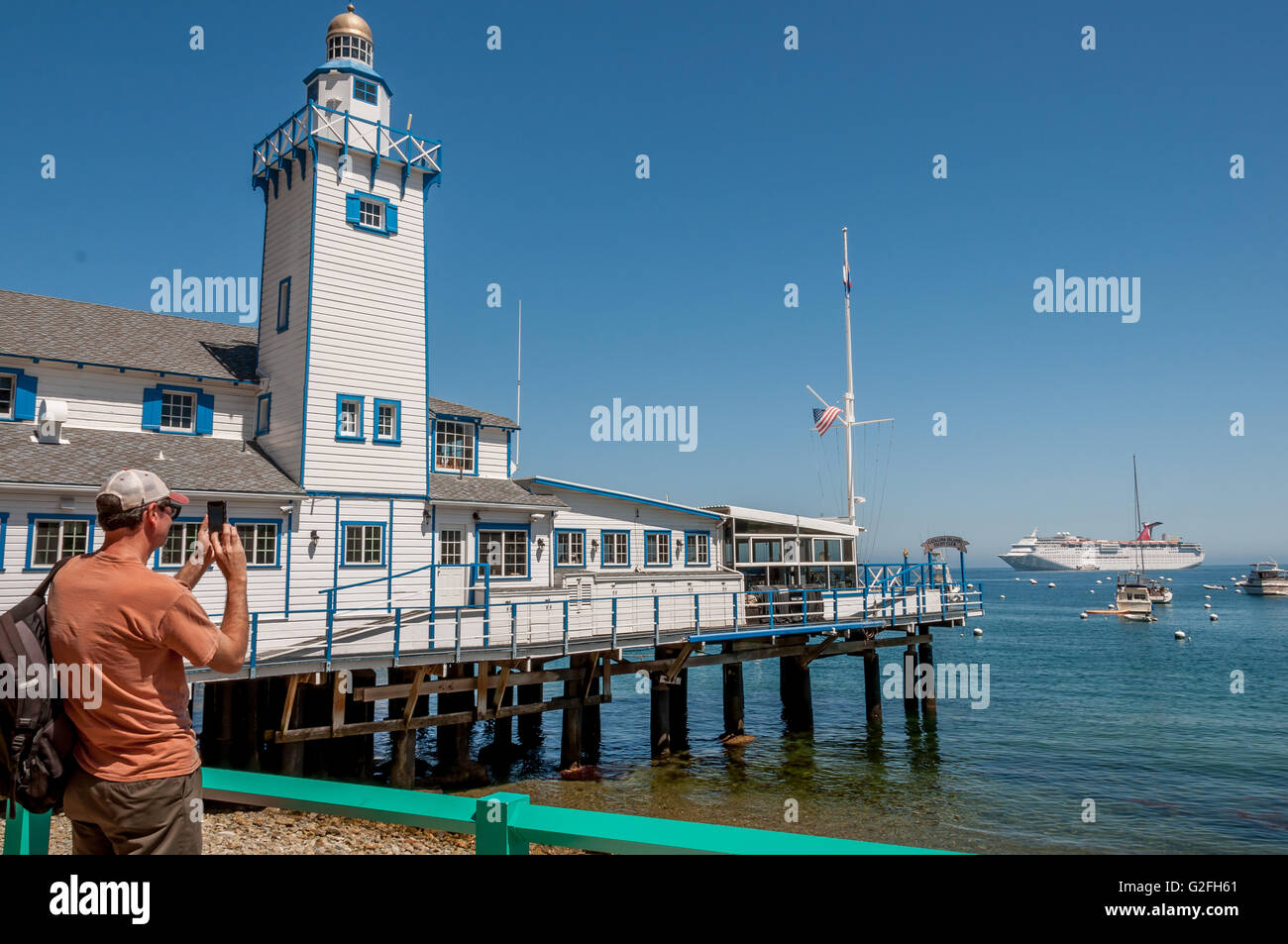 Bateau de croisière touristique  + passager prenant photo sur smart phone at Catalina Harbour à Avalon avec Carnival Cruise ship et la voile Banque D'Images