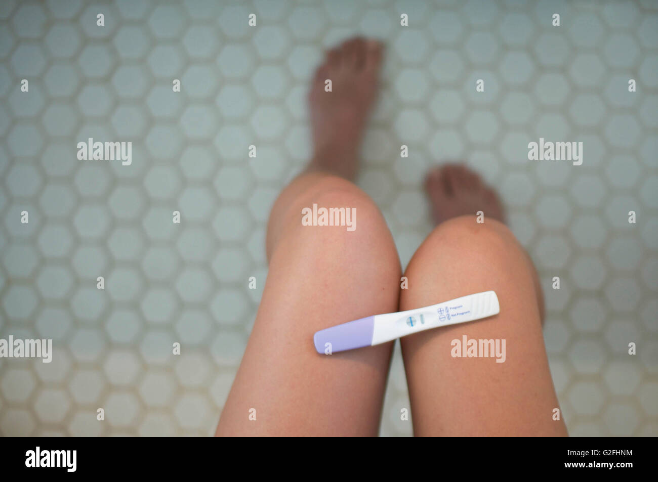 Test de grossesse positif sur les jambes de la femme dans la salle de bains, High Angle View Banque D'Images