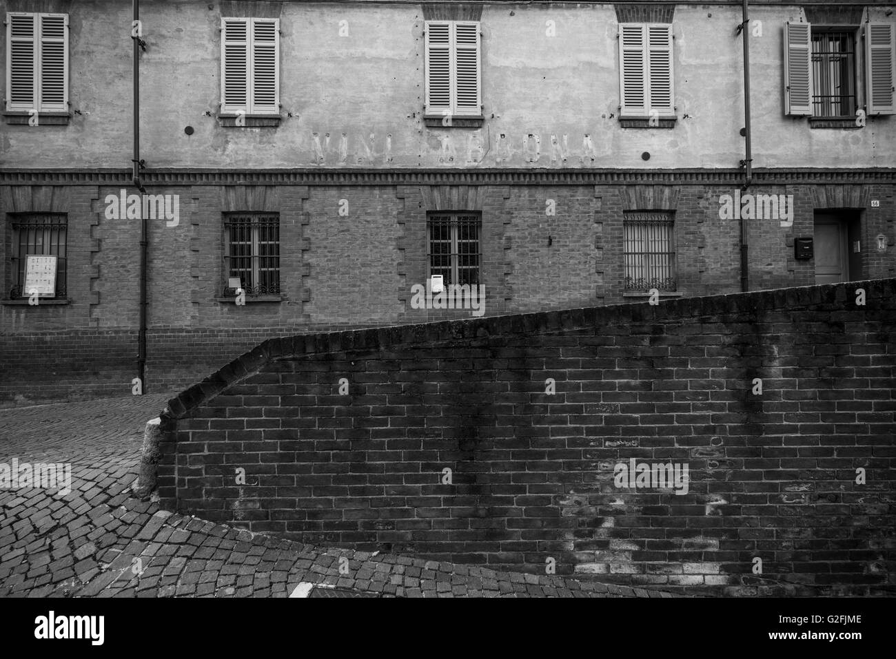 Rue Pavée, divisé par le mur de briques avec des capacités en arrière-plan, Barolo, Italie Banque D'Images