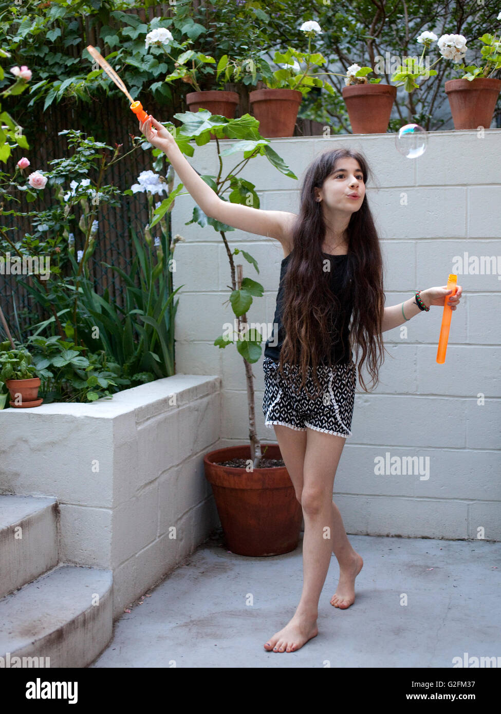 Jeune fille au balcon arrière blowing bubbles Banque D'Images