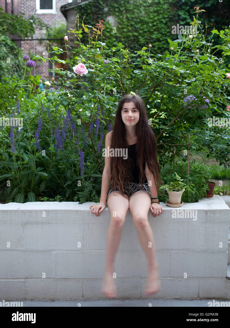 Jeune fille enfant kid porche arrière posées posing cour home garden wall roses salvia pivoine allium Banque D'Images