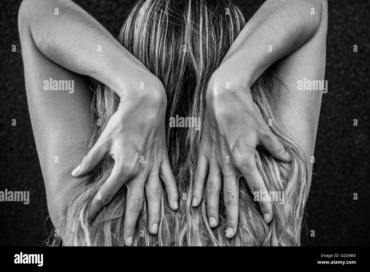 Vue arrière de la femme qui remonte à toucher son épaule avec ses mains Banque D'Images