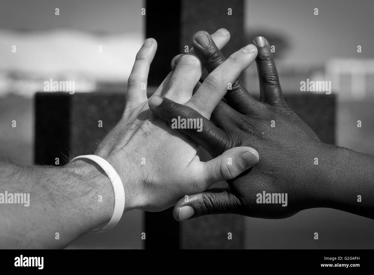 Deux mains entrelacées en face de Cross Banque D'Images