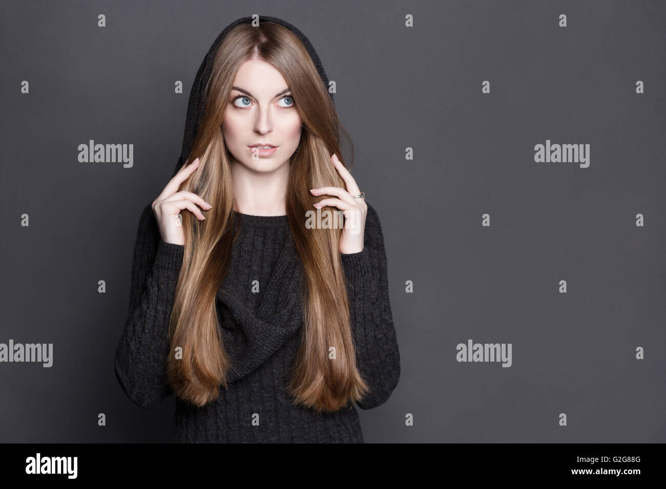 Belle jeune femme aux longs cheveux blond foncé, magnifique. Elle est vêtue de gris chaud robe tricot avec une capuche. Elle a perfect c Banque D'Images
