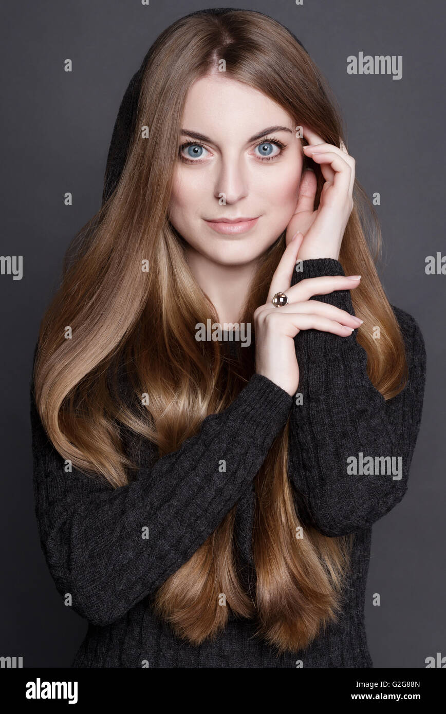 Jeune femme séduisante avec de longs cheveux blond foncé, magnifique et de grands yeux bleus. Elle est vêtue de gris chaud robe tricot avec un ho Banque D'Images