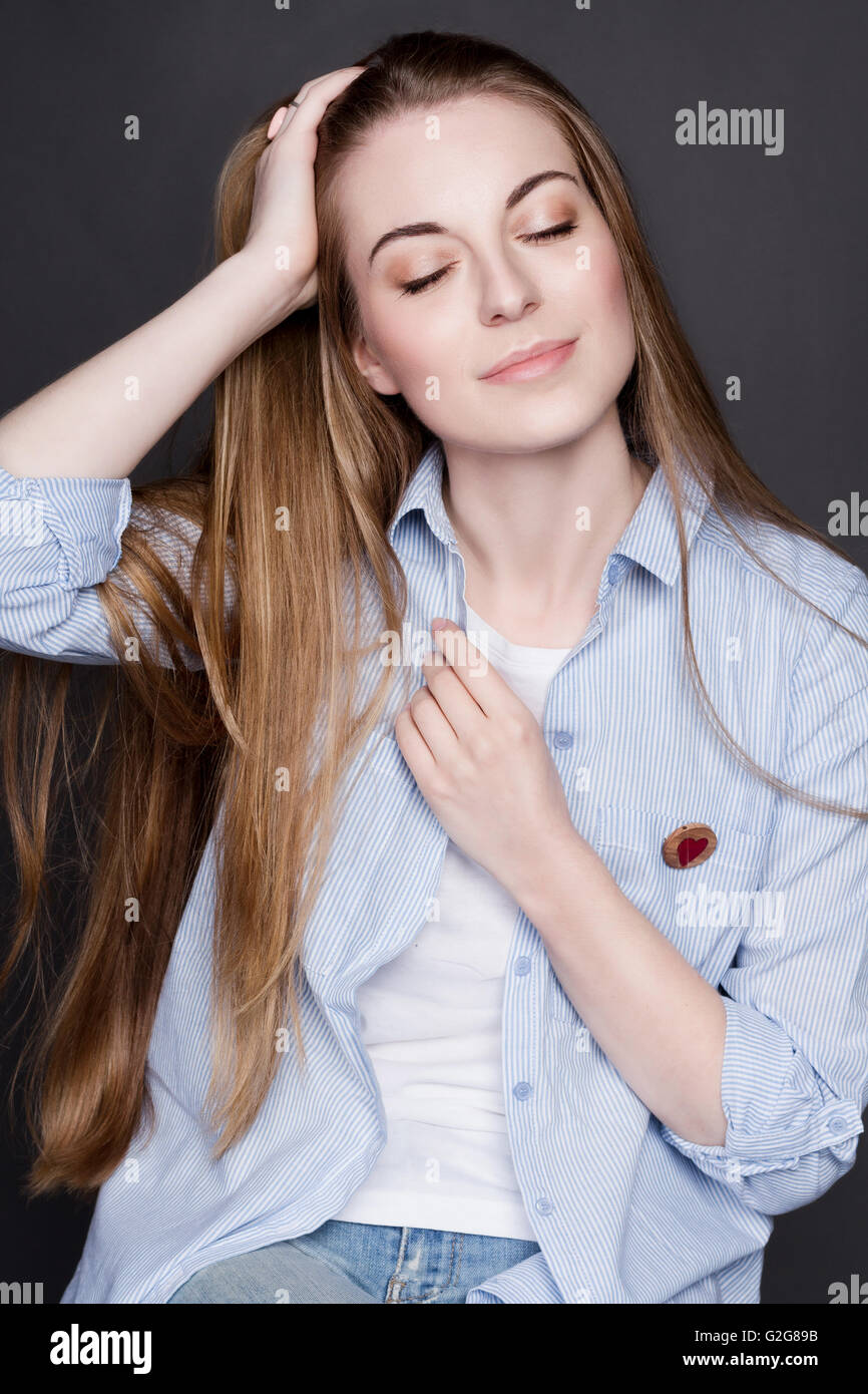 Portrait d'une belle jeune fille blonde. Elle porte une chemise en jean et un T-shirt blanc. Elle a de magnifiques cheveux brillants et cle Banque D'Images