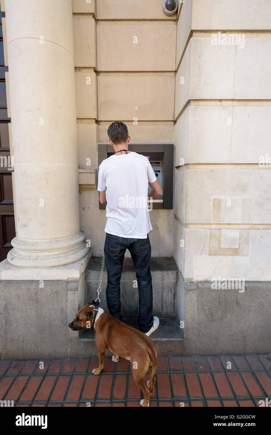 L'homme avec son chien en laisse utilise un distributeur ATM machine à Chelmsford Essex en Angleterre Banque D'Images