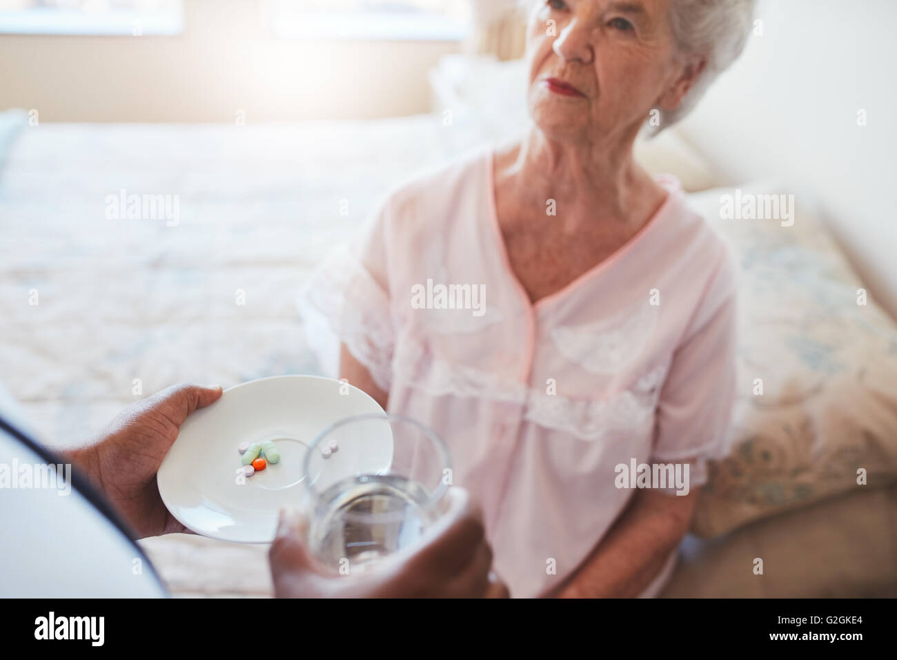 Senior woman sitting on bed et d'infirmière à domicile donner des médicaments. Main de l'infirmière donnant des pilules pour personnes âgées patiente. Banque D'Images