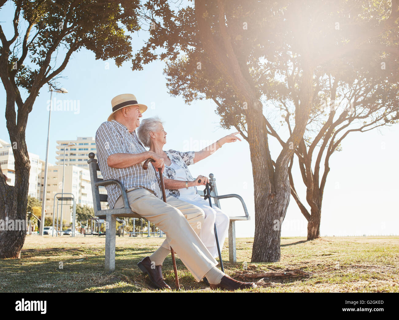 Tourné en plein air d'un couple assis sur un banc de parc avec femme montrant quelque chose d'intéressant à son mari. Couple de retraités Banque D'Images