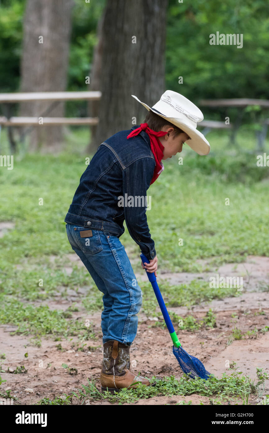 Un jeune garçon en tenue de cow-boy la collecte des grenouilles et des insectes à McKinney Falls State Park, Austin, Texas. USA. Banque D'Images