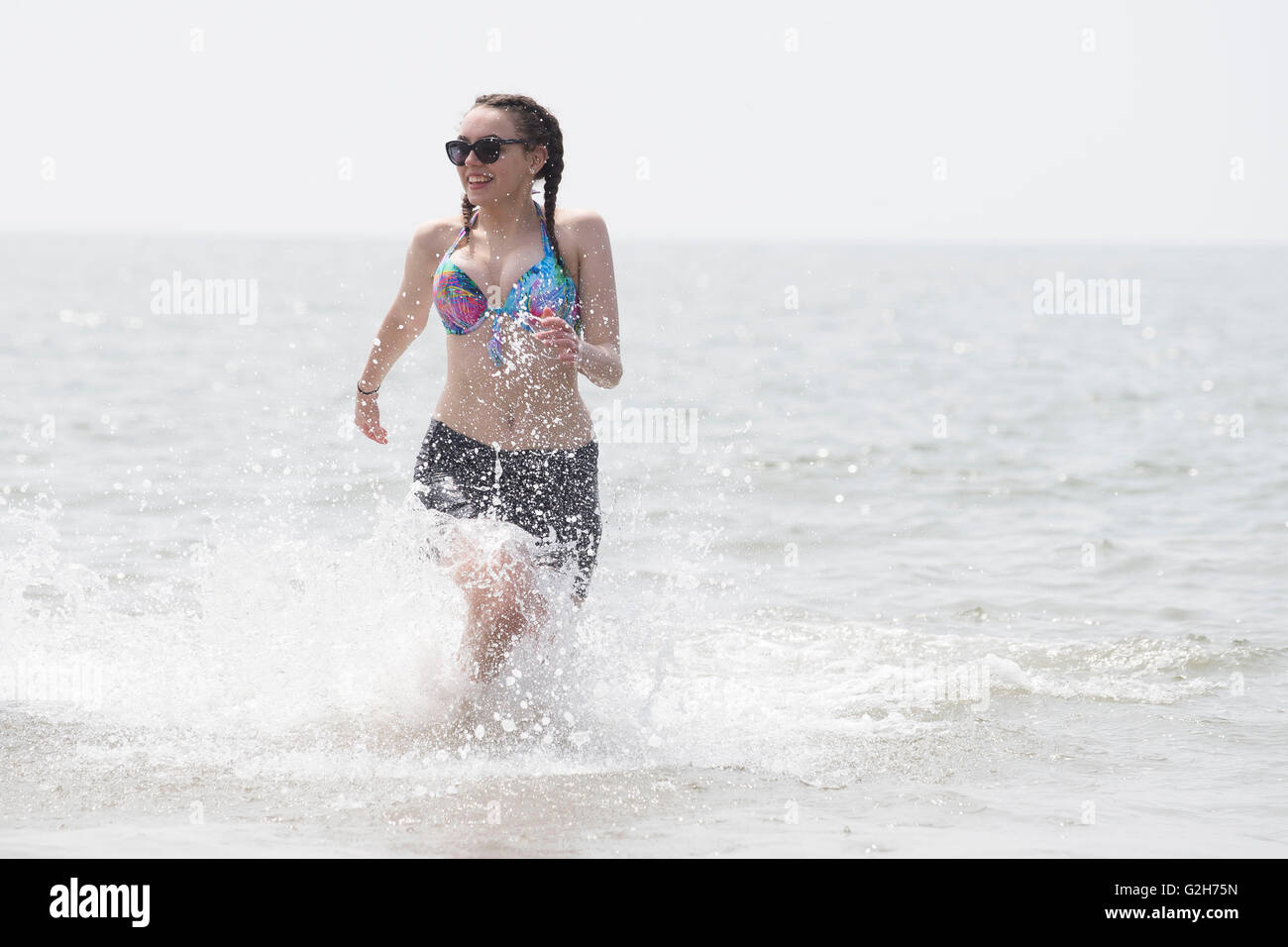 Une femme cools off dans la mer par beau temps ensoleillé chaud dans la région de Barry, au Pays de Galles. Banque D'Images